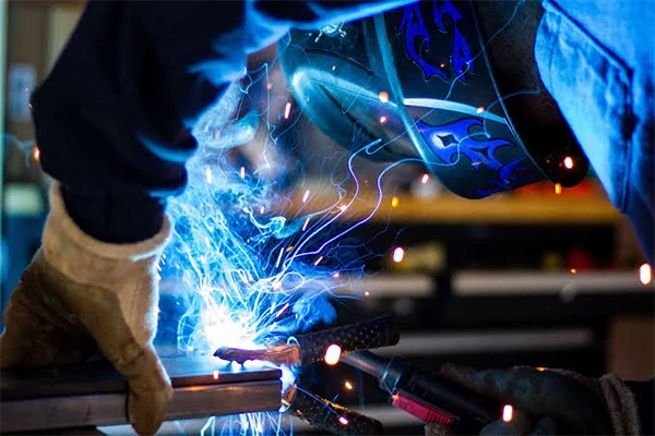 Operator using a handheld laser welding gun on a metal seam in a workshop